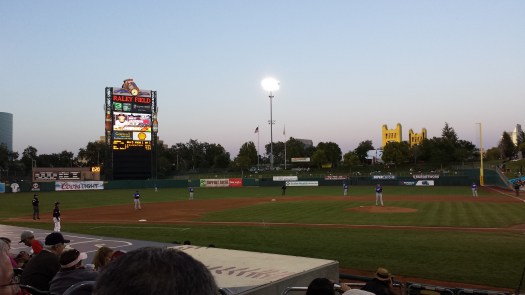 The sun sets at River Cats Ballpark in West Sacramento. The golden Tower Bridge is in the middle distance.